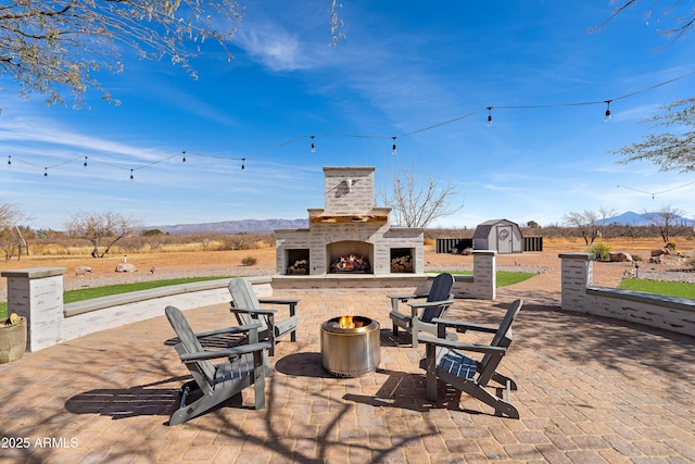 view of patio featuring a shed, a mountain view, and an outdoor fireplace