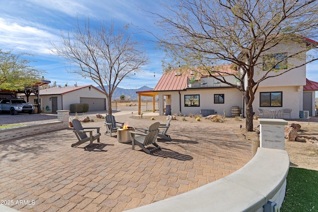 view of patio / terrace featuring a mountain view, central AC, and an outdoor fire pit