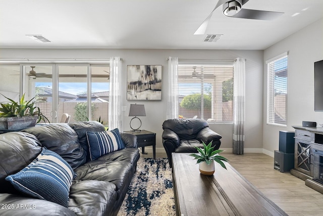 living room featuring a ceiling fan, visible vents, and light wood-type flooring