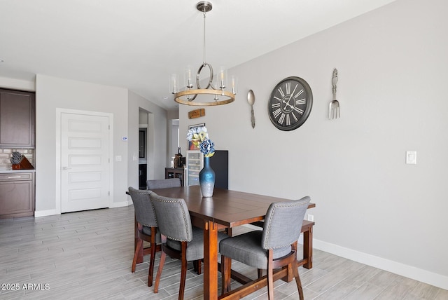 dining room with light wood-style floors, baseboards, and an inviting chandelier
