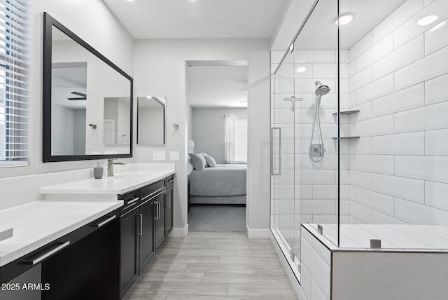 full bathroom featuring connected bathroom, vanity, baseboards, wood finished floors, and a stall shower