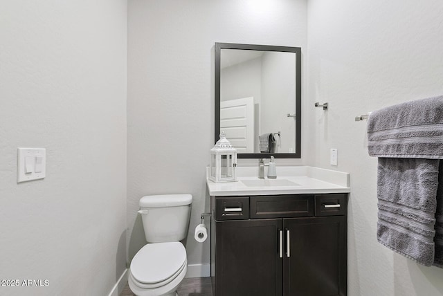 bathroom with vanity, baseboards, and toilet