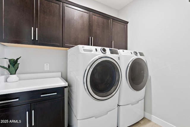 washroom with cabinet space, baseboards, washing machine and dryer, and light wood-style floors