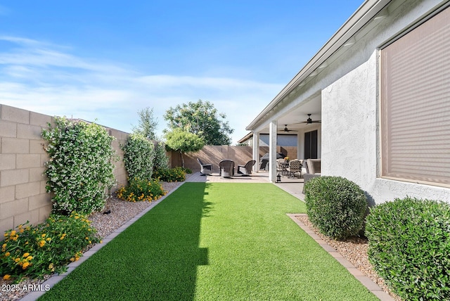 view of yard featuring a fenced backyard, ceiling fan, and a patio area
