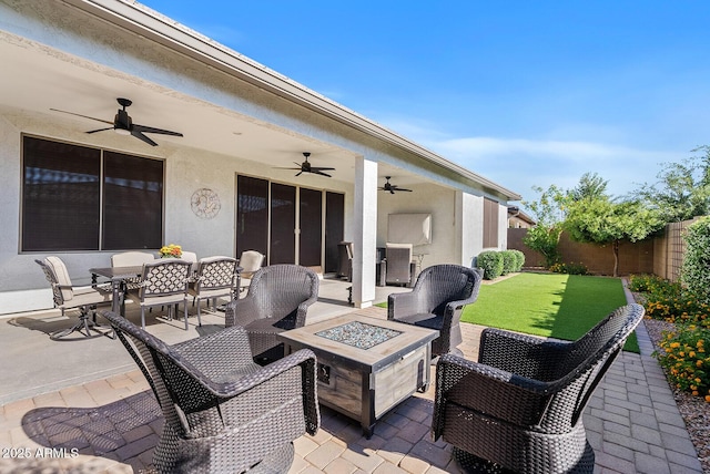 view of patio featuring ceiling fan, a fire pit, a fenced backyard, and outdoor dining space