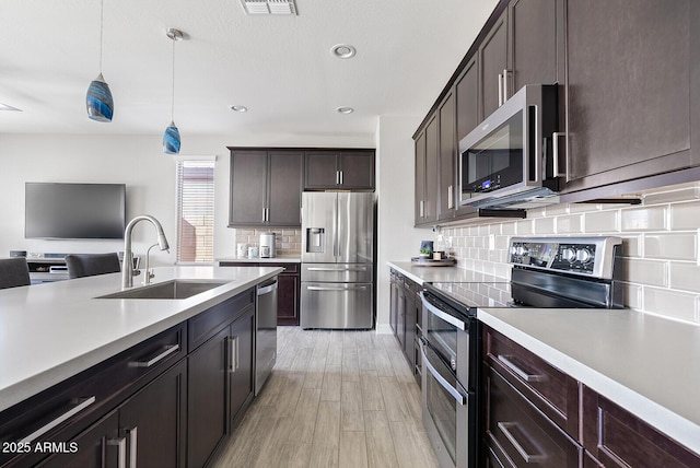 kitchen featuring light countertops, appliances with stainless steel finishes, a sink, and tasteful backsplash