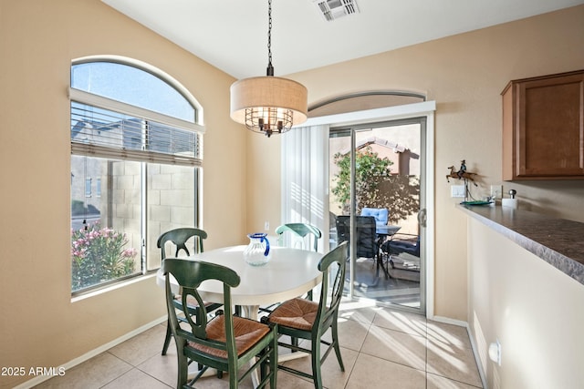 tiled dining room with an inviting chandelier