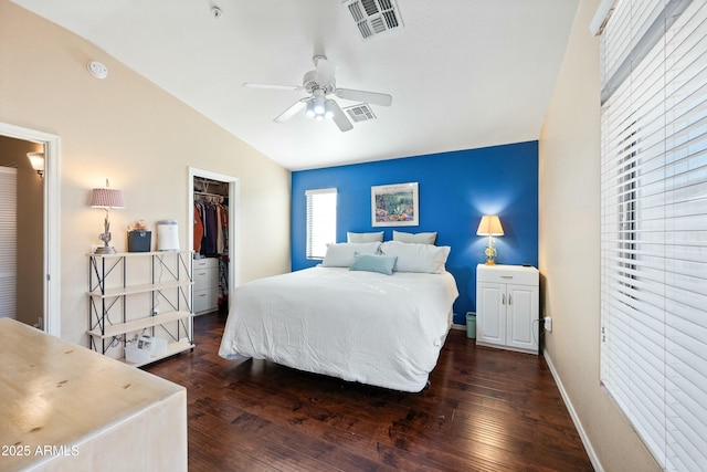 bedroom featuring ceiling fan, dark wood-type flooring, a walk in closet, a closet, and lofted ceiling