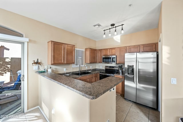 kitchen featuring sink, light tile patterned floors, kitchen peninsula, and appliances with stainless steel finishes