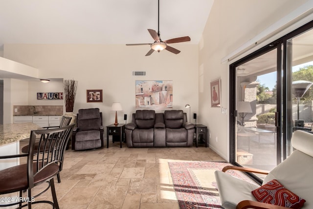 living room with ceiling fan and a towering ceiling