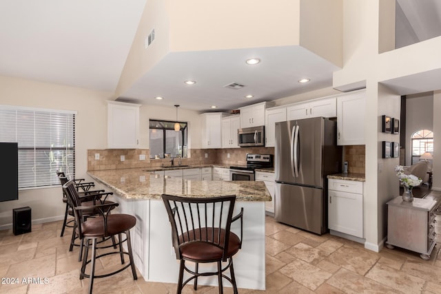 kitchen with white cabinets, a kitchen breakfast bar, hanging light fixtures, appliances with stainless steel finishes, and kitchen peninsula