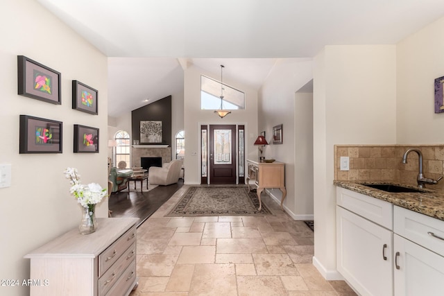 foyer entrance with a tile fireplace, high vaulted ceiling, and sink