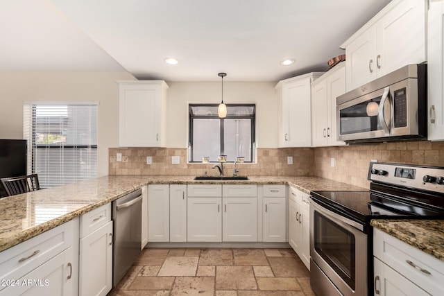 kitchen featuring light stone countertops, white cabinetry, stainless steel appliances, and hanging light fixtures