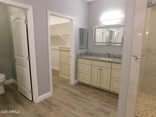 bathroom with a tile shower, vanity, hardwood / wood-style flooring, and toilet