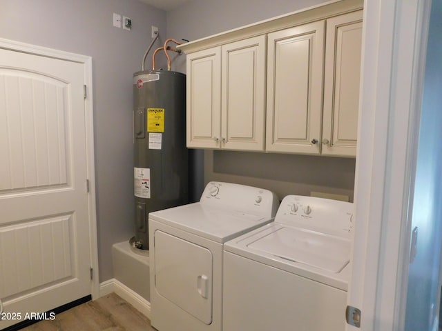 clothes washing area with cabinets, water heater, washing machine and clothes dryer, and light wood-type flooring