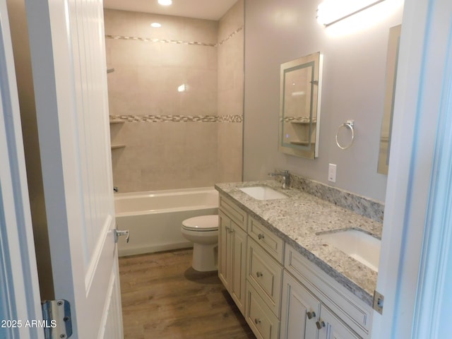 full bathroom featuring hardwood / wood-style flooring, tiled shower / bath, vanity, and toilet