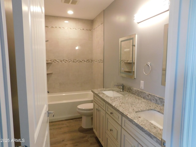 full bathroom with vanity, tiled shower / bath, wood-type flooring, and toilet