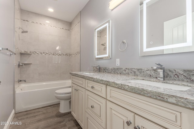 full bathroom with vanity, hardwood / wood-style floors, tiled shower / bath combo, and toilet