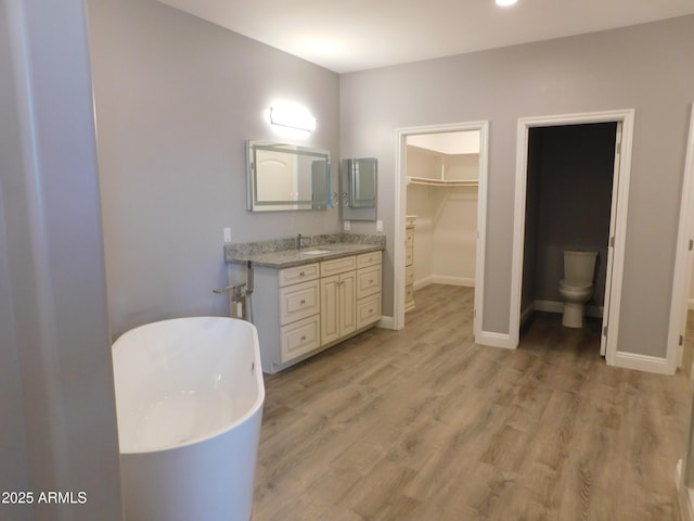 bathroom with hardwood / wood-style flooring, vanity, a bath, and toilet