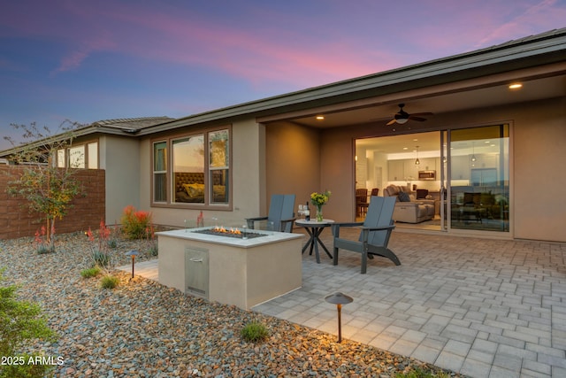 patio terrace at dusk with a fire pit and ceiling fan