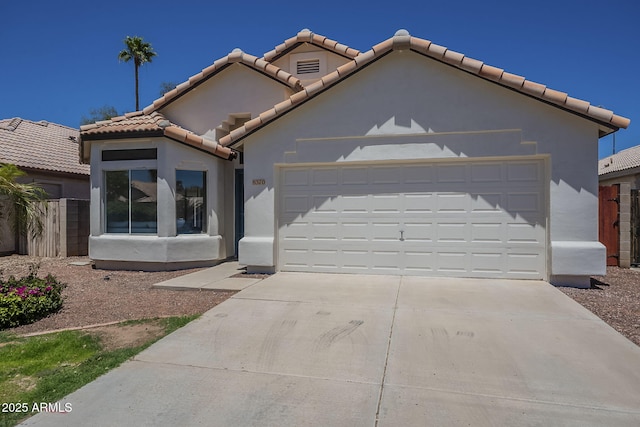 view of front of property featuring an attached garage, driveway, a tile roof, and stucco siding