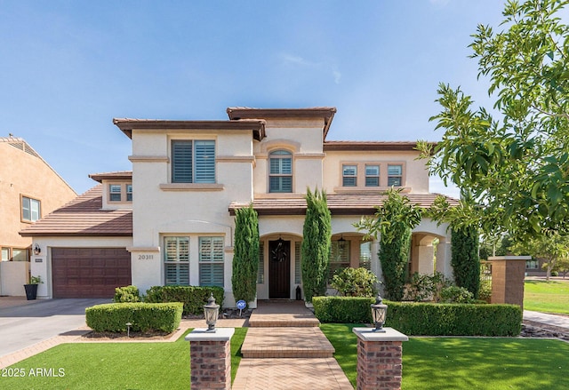 mediterranean / spanish-style house featuring driveway, a front lawn, a tile roof, and stucco siding