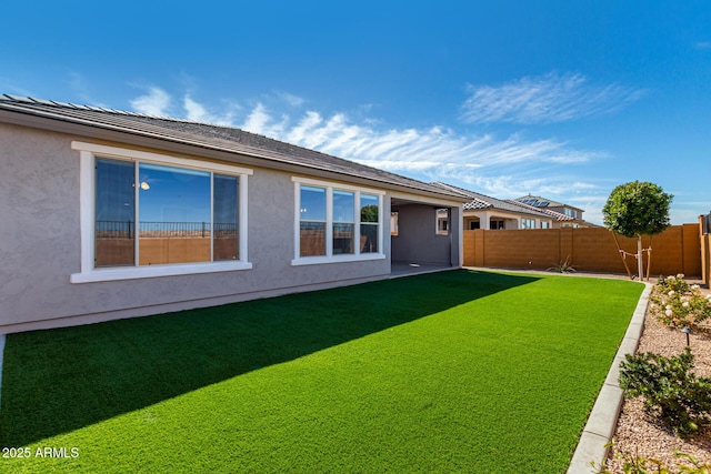 back of property featuring a yard, a fenced backyard, and stucco siding