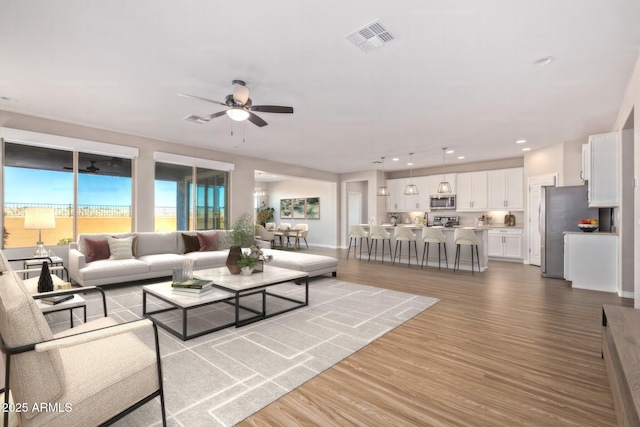 living area with recessed lighting, wood finished floors, visible vents, and a ceiling fan