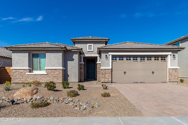 prairie-style house featuring a garage, decorative driveway, stone siding, and stucco siding