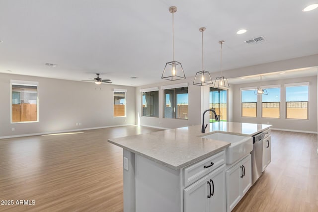 kitchen with a sink, visible vents, open floor plan, stainless steel dishwasher, and light wood finished floors