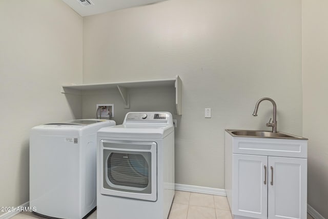 laundry area featuring cabinet space, baseboards, separate washer and dryer, a sink, and light tile patterned flooring