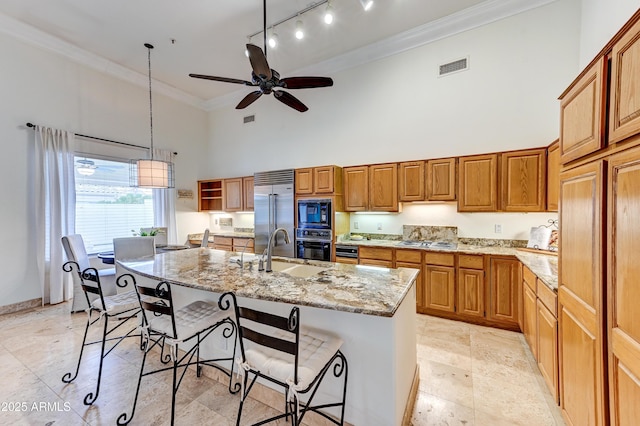 kitchen featuring a high ceiling, black appliances, a sink, ornamental molding, and light stone countertops