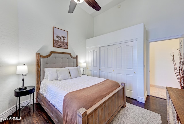 bedroom with dark wood finished floors, high vaulted ceiling, a closet, ceiling fan, and baseboards