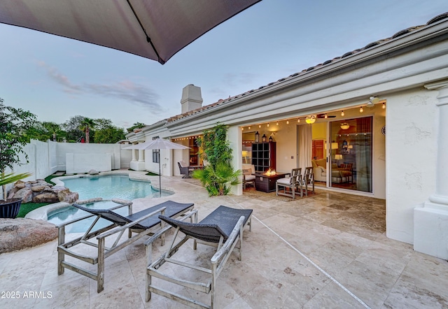 view of swimming pool featuring a patio, an outdoor fire pit, a fenced backyard, and an in-ground hot tub