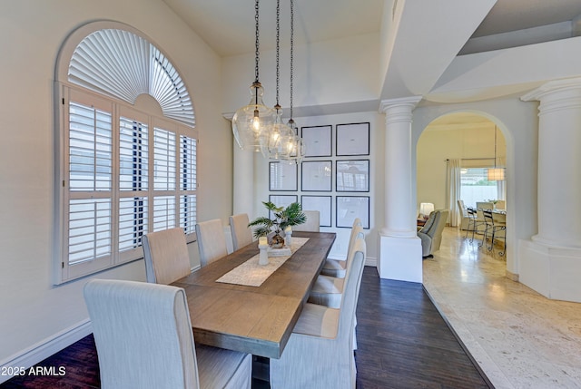 dining room with ornate columns, arched walkways, baseboards, a chandelier, and wood finished floors