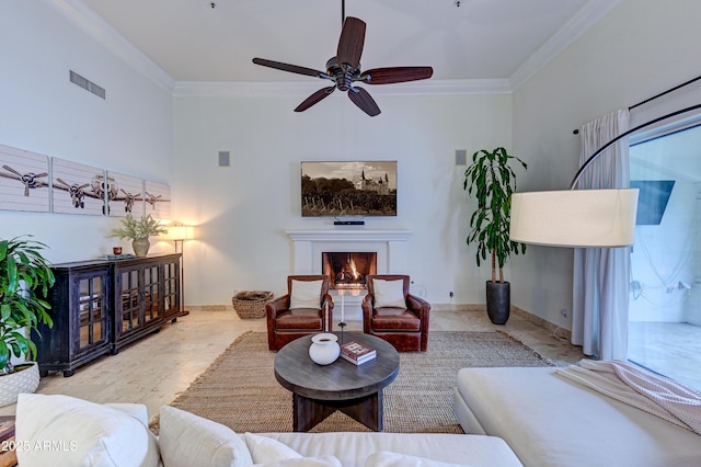 living room with crown molding, a lit fireplace, ceiling fan, and a high ceiling