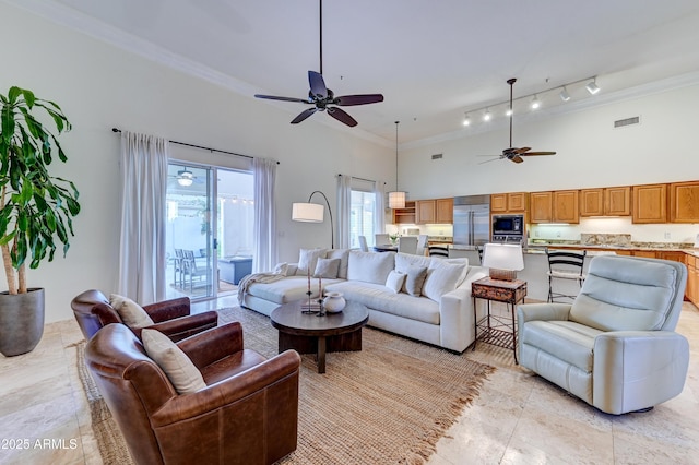 living area with ceiling fan, a high ceiling, crown molding, and light tile patterned flooring
