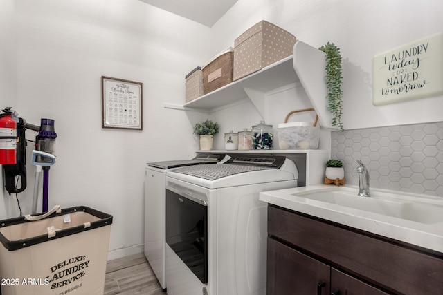 laundry room featuring cabinets, separate washer and dryer, sink, and light hardwood / wood-style floors