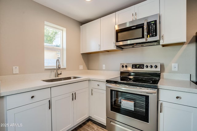 kitchen with appliances with stainless steel finishes, a sink, white cabinets, and light countertops