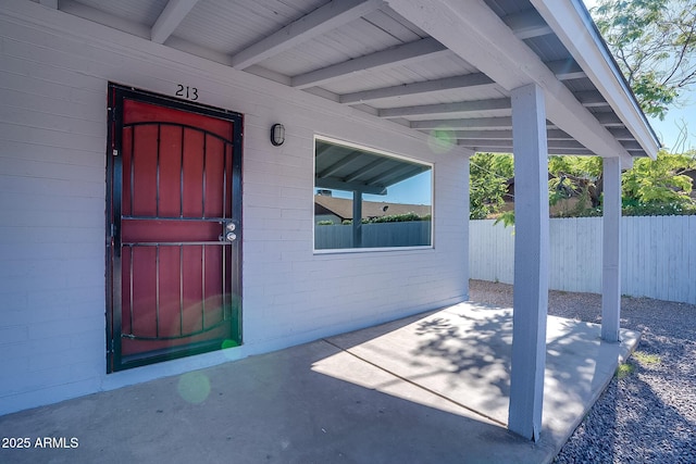 property entrance with fence, concrete block siding, and a patio area