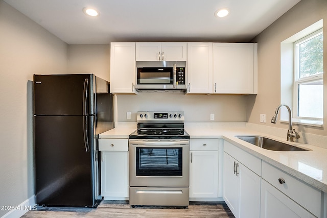 kitchen featuring stainless steel appliances, a sink, light wood-type flooring, white cabinets, and recessed lighting
