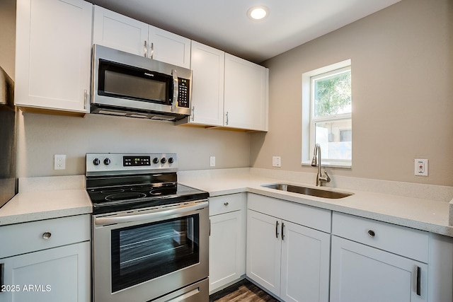 kitchen featuring appliances with stainless steel finishes, a sink, light countertops, white cabinets, and recessed lighting