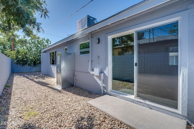 view of side of property with fence, concrete block siding, and a chimney