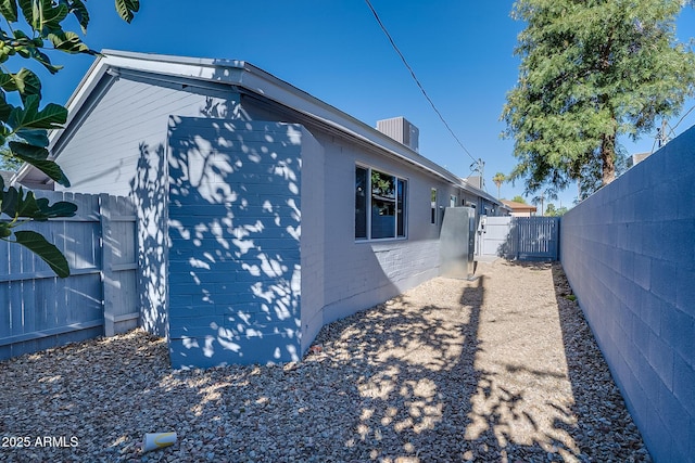 view of home's exterior with a gate, a fenced backyard, and brick siding