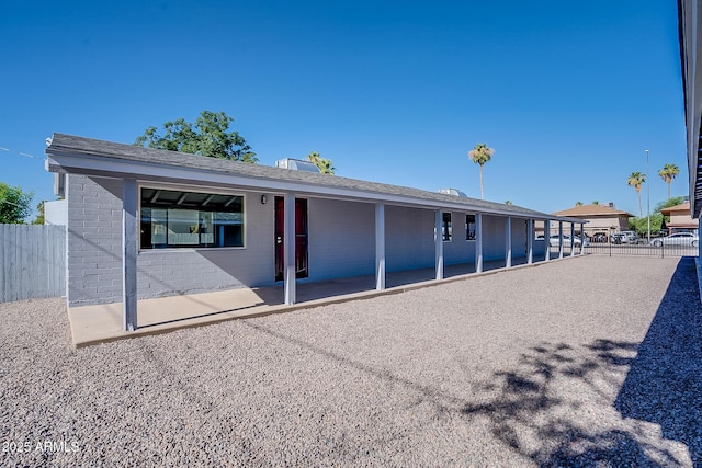 rear view of property featuring fence, a patio, and brick siding