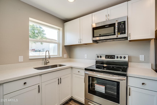 kitchen with appliances with stainless steel finishes, a sink, light countertops, and white cabinets