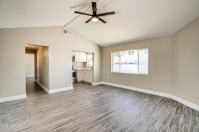 unfurnished living room with a ceiling fan, wood finished floors, baseboards, and a sink