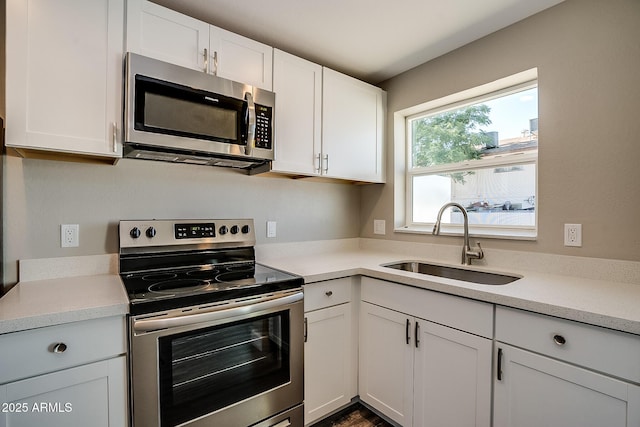 kitchen featuring appliances with stainless steel finishes, a sink, white cabinetry, and light countertops
