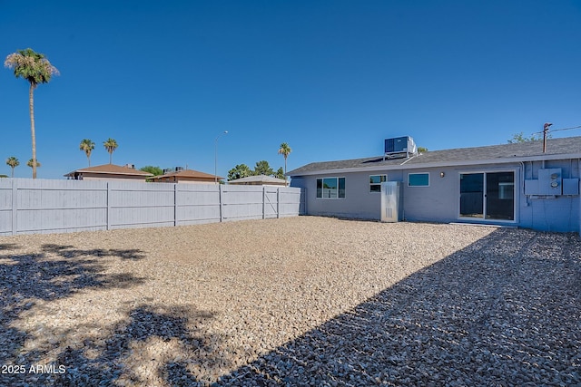 back of house with a fenced backyard and central AC