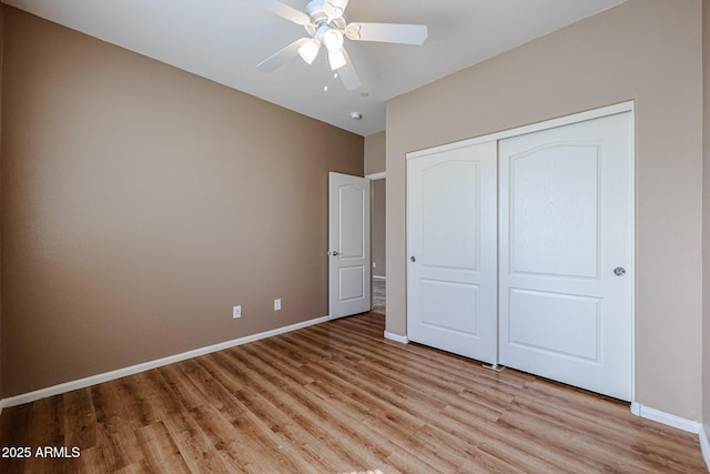unfurnished bedroom with a closet, light wood-style flooring, a ceiling fan, and baseboards